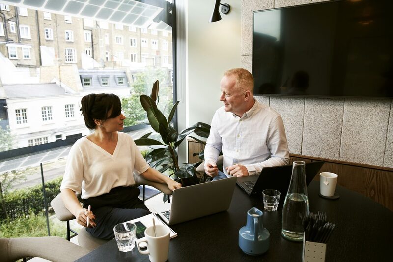 Consultant and customer talking across a desk in a bright meeting room