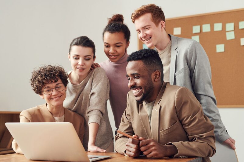 Sales team members collaborating around a laptop in a bright office
