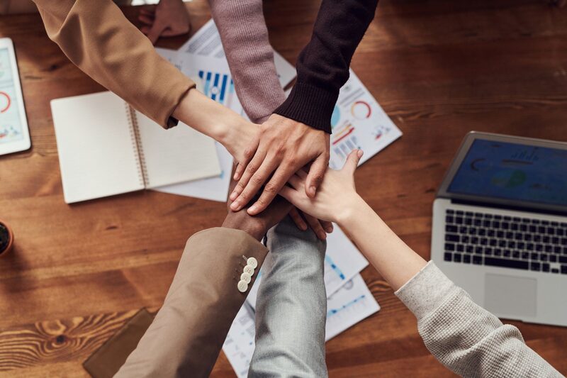 Team members joining hands over a desk covered in campaign notes